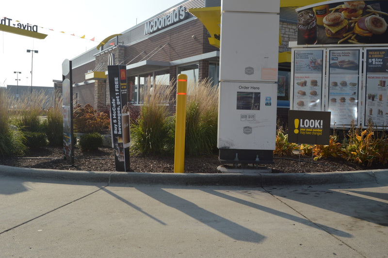 Flat Top Bollard Cover in yellow with white/silver tape at a Drive-Thru 