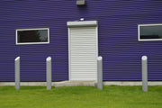 Purple building with a white door and security bollards in front
