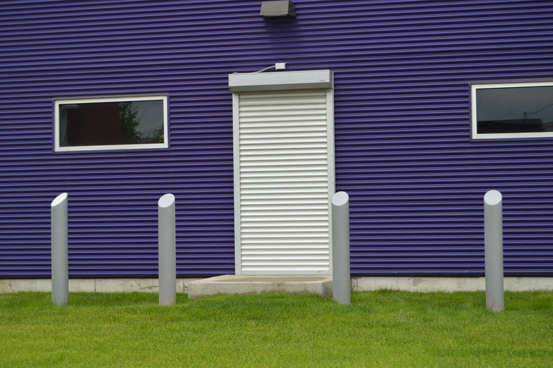 Purple building with a white door and security bollards in front