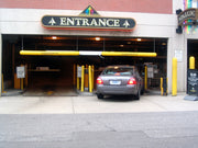 Car entering a parking garage with an 'Entrance' sign above the gate.