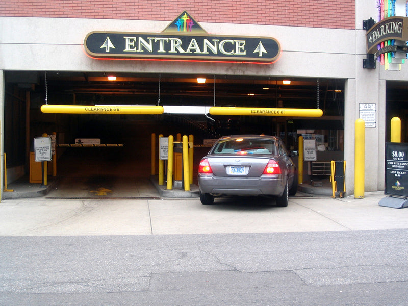 Car entering a parking garage with an 'Entrance' sign above the gate.