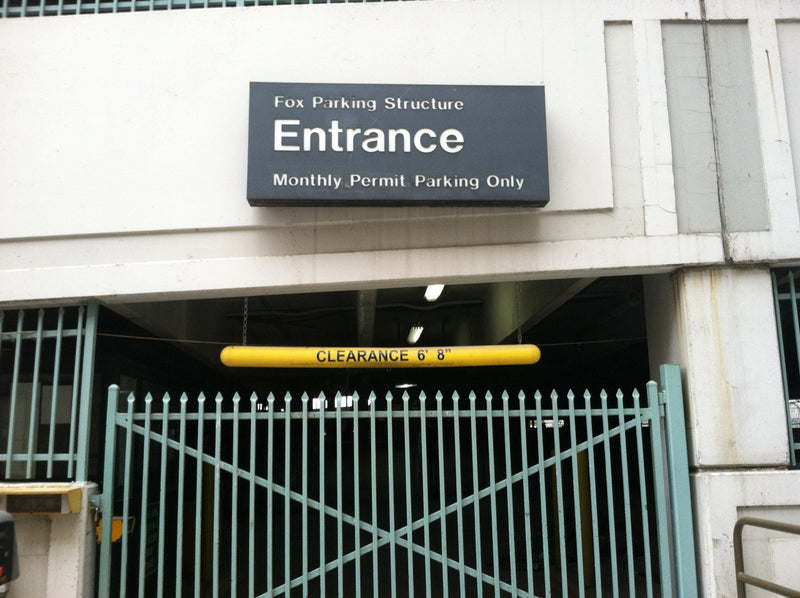 Entrance sign for a parking structure with a fence in front